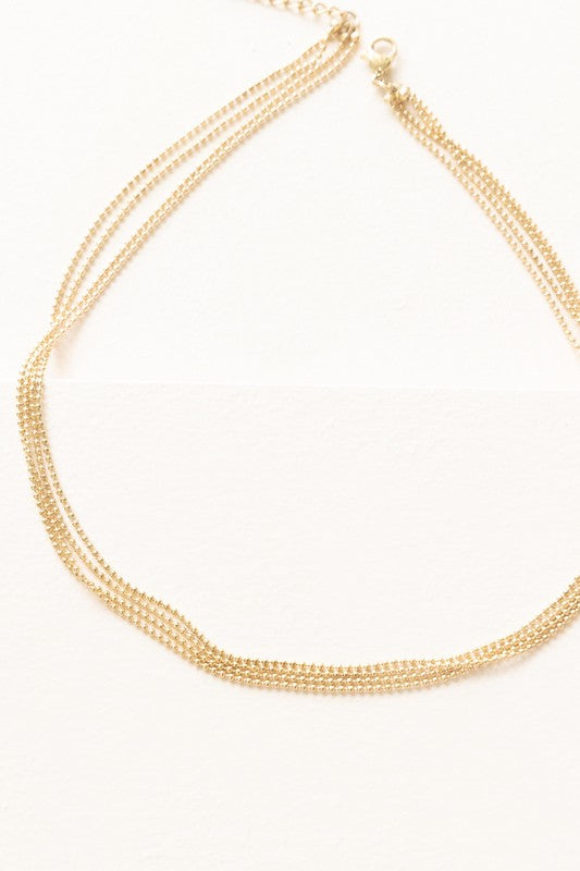 The Juliet Layered Necklace, plated in 14k gold, shines brilliantly against a white background, highlighting the elegance of stainless steel jewelry.