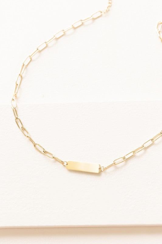 Plate Oval Chain Necklace showcases a bar pendant and sleek toggle clasp, plated with 14k gold on high-quality stainless steel against a light background.