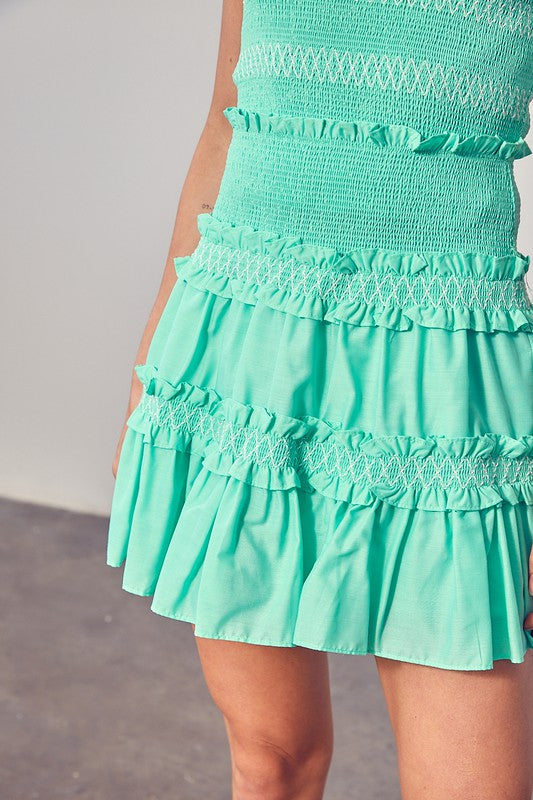 Close-up of a person showcasing the Tiered Ruffle Skirt in turquoise, featuring shirred detailing and multiple ruffled layers—a perfect example of trendy fashion.