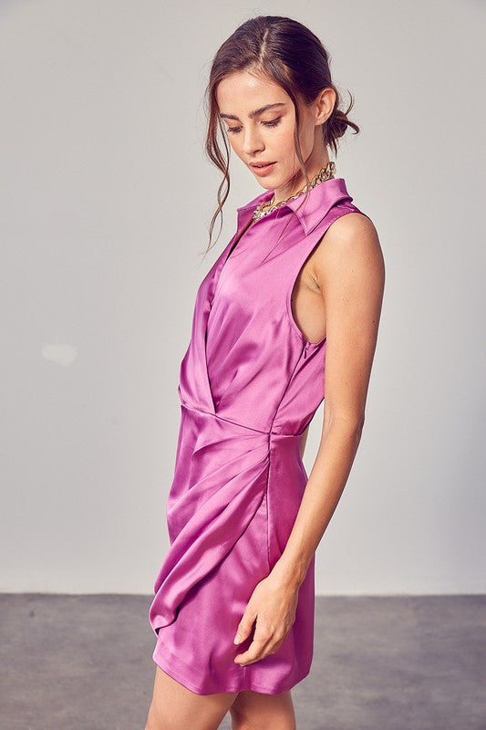 A woman in a sleeveless white Collar Wrap Dress stands in a bright room, looking to the side. She is wearing a gold chain necklace.