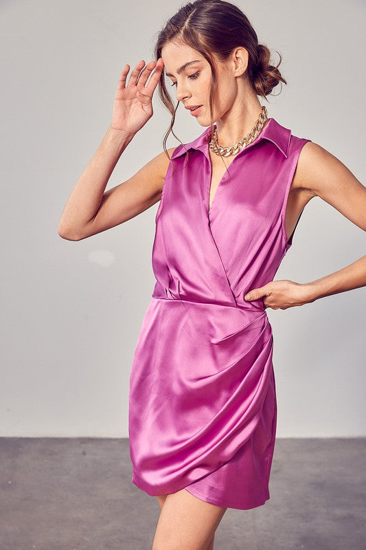 A woman in a sleeveless white Collar Wrap Dress stands in a bright room, looking to the side. She is wearing a gold chain necklace.