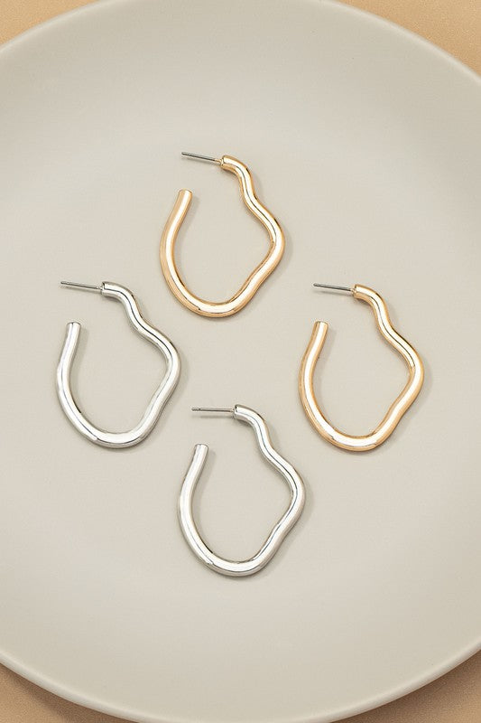 The Irregular shape metal hoop earrings, featuring a shiny gold finish and post back closures, are displayed on a neutral background.