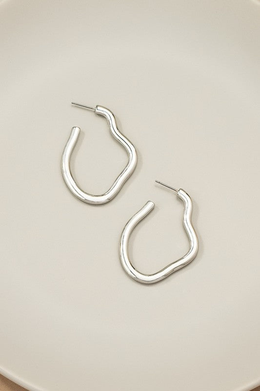 The Irregular shape metal hoop earrings, featuring a shiny gold finish and post back closures, are displayed on a neutral background.