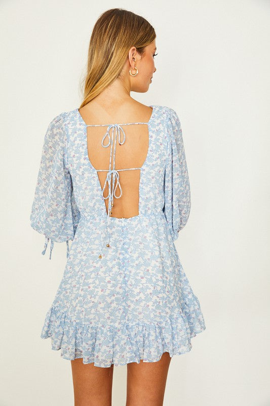 A person wearing a Floral Print Babydoll Mini Dress in light blue with three-quarter sleeves poses against a plain background.