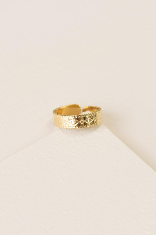 The Dol Adjustable Ring, with its 14k gold plating and intricate engravings, rests elegantly on a light surface, exuding timeless charm and sophistication.