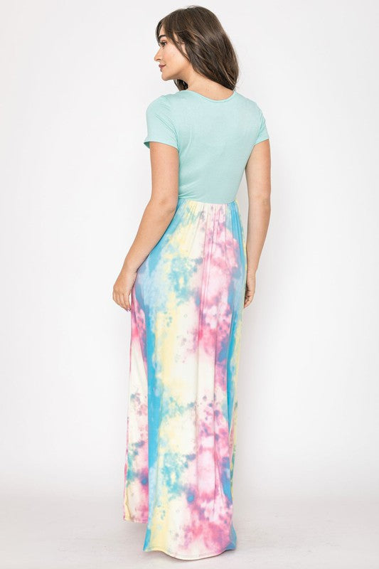 A woman in a gray top stylishly pairs her vibrant Two Tone Tie Dye Maxi Dress, standing against a plain background.