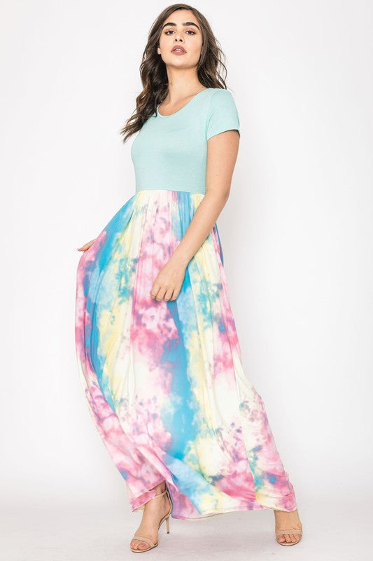 A woman in a gray top stylishly pairs her vibrant Two Tone Tie Dye Maxi Dress, standing against a plain background.