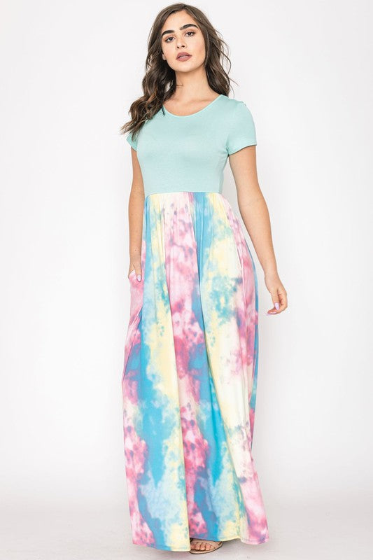 A woman in a gray top stylishly pairs her vibrant Two Tone Tie Dye Maxi Dress, standing against a plain background.