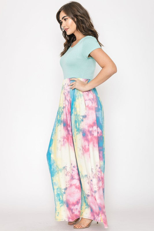 A woman in a gray top stylishly pairs her vibrant Two Tone Tie Dye Maxi Dress, standing against a plain background.