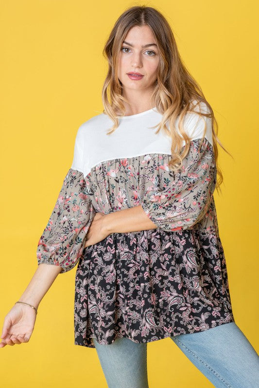 A woman elegantly poses against a vibrant yellow background, showcasing a Three Tiered Bishop Sleeve Paisley Floral Tunic.