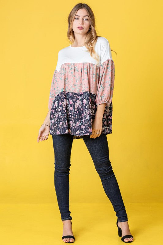 A person wearing a Three Tiered Bishop Sleeve Paisley Floral Tunic and jeans stands gracefully against a vivid yellow background.