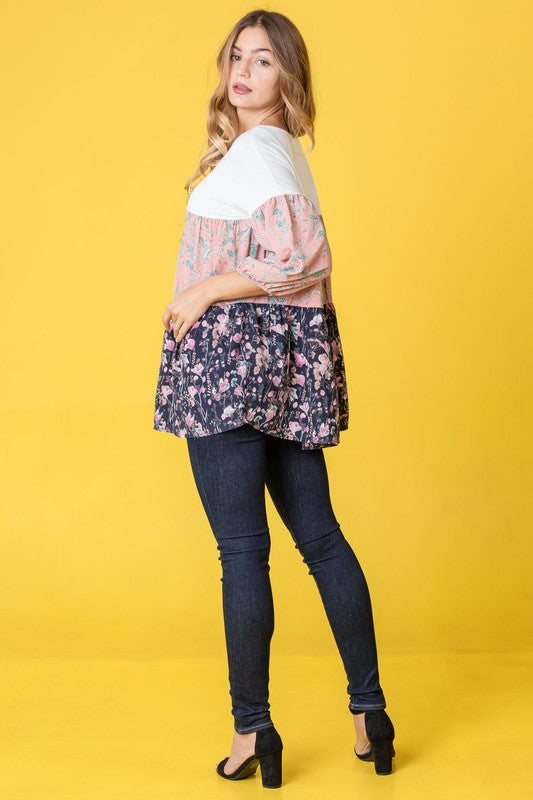 A person wearing a Three Tiered Bishop Sleeve Paisley Floral Tunic and jeans stands gracefully against a vivid yellow background.