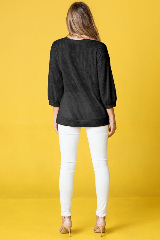 Wearing a Plus Solid Waffle Knit Top and white pants, a woman stands gracefully against a vibrant yellow background.