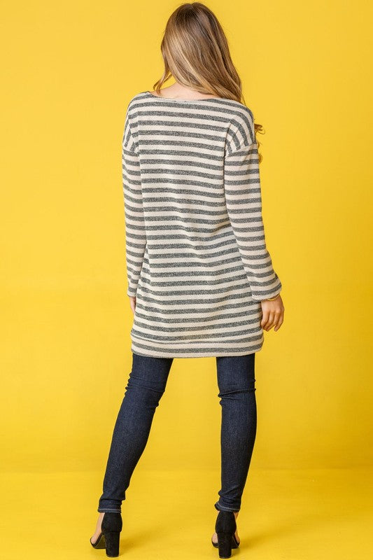 A person confidently stands against a vibrant yellow background, with their hands in pockets, showcasing the Terry Stripe Reverse Sleeve Tunic.