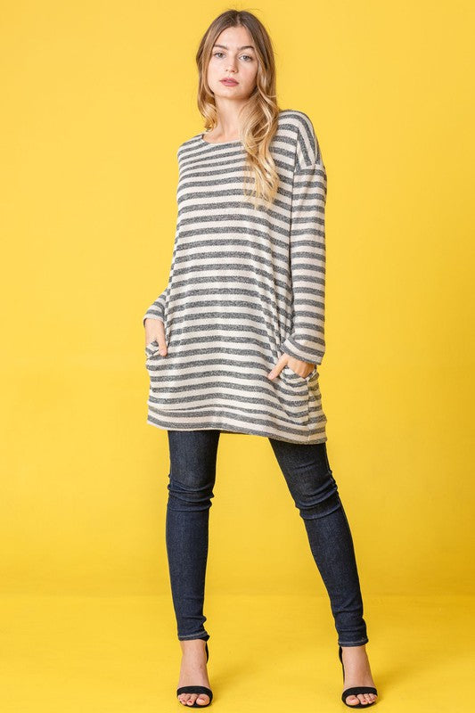 A person confidently stands against a vibrant yellow background, with their hands in pockets, showcasing the Terry Stripe Reverse Sleeve Tunic.