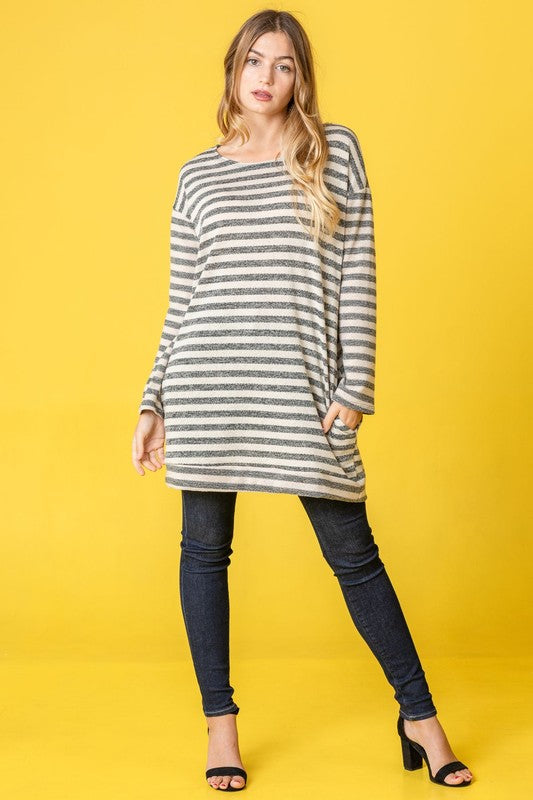 A person confidently stands against a vibrant yellow background, with their hands in pockets, showcasing the Terry Stripe Reverse Sleeve Tunic.