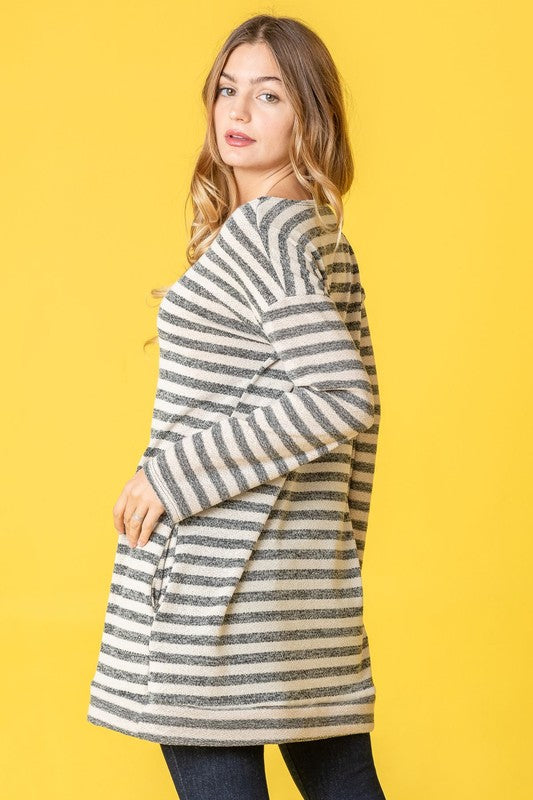 A person confidently stands against a vibrant yellow background, with their hands in pockets, showcasing the Terry Stripe Reverse Sleeve Tunic.