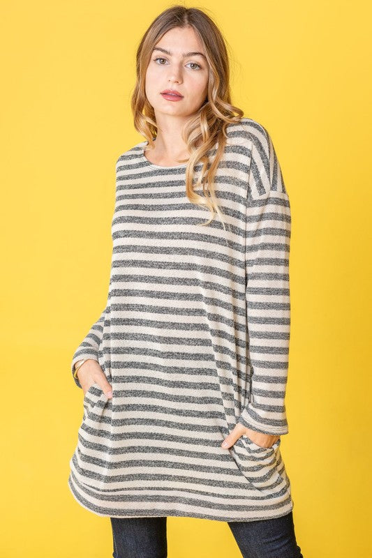 A person confidently stands against a vibrant yellow background, with their hands in pockets, showcasing the Terry Stripe Reverse Sleeve Tunic.