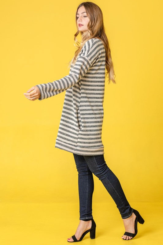 A person confidently stands against a vibrant yellow background, with their hands in pockets, showcasing the Terry Stripe Reverse Sleeve Tunic.