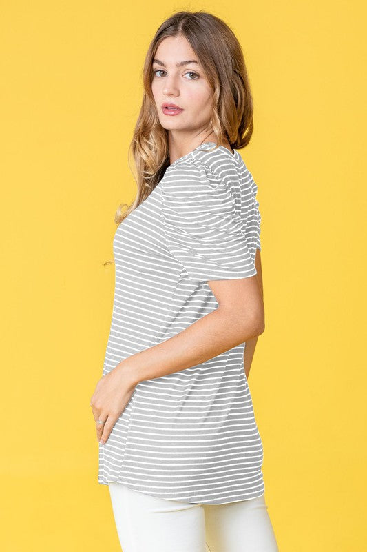 A woman presents the Stripe Puff Ruched Sleeve Top, a navy and white shirt with ruched sleeves, against a vibrant yellow background.