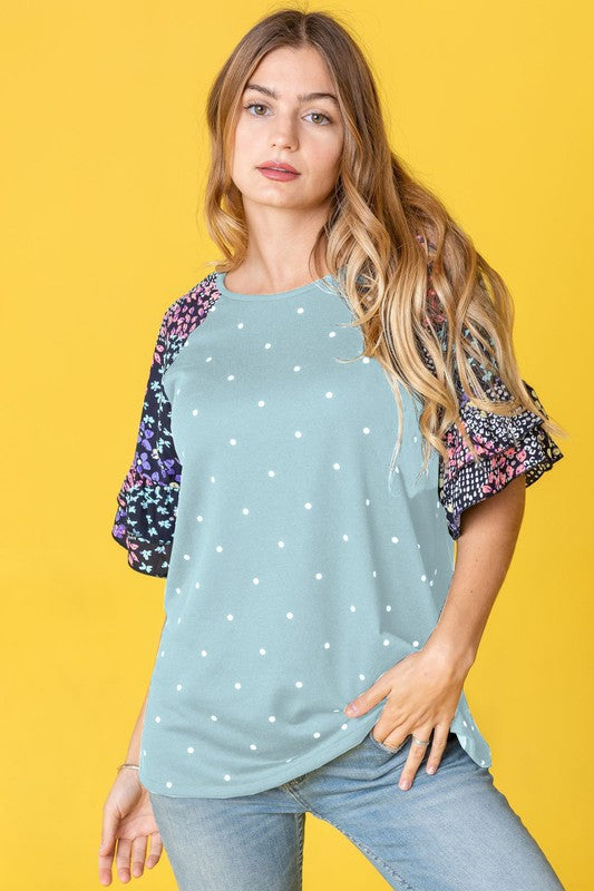 A person wearing the Polka Dot Print Ruffle Sleeve Top is standing against a bold yellow background.