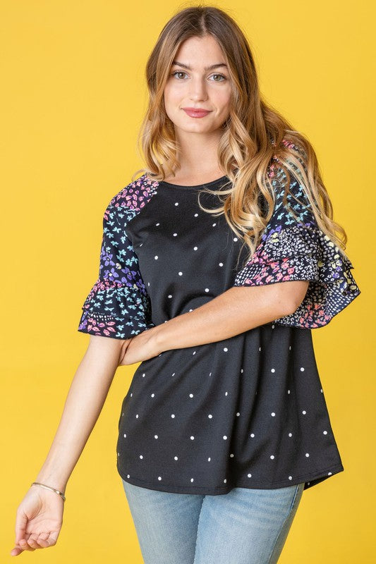 A person wearing the Polka Dot Print Ruffle Sleeve Top is standing against a bold yellow background.