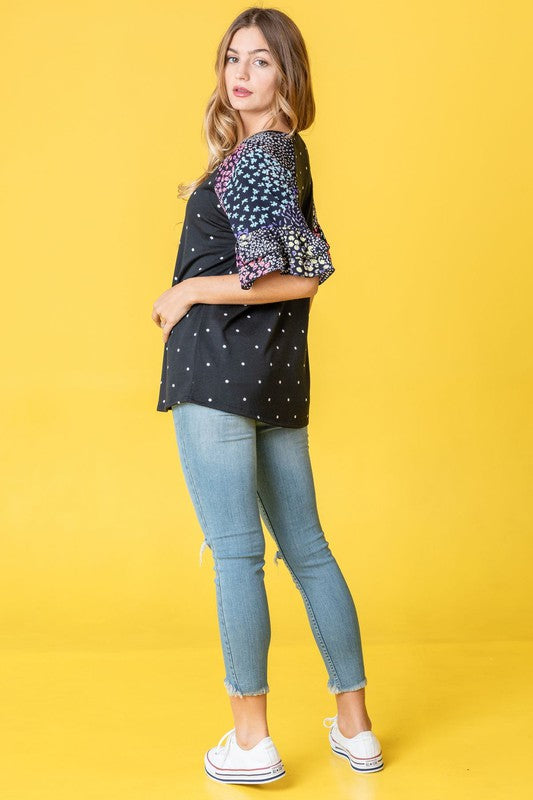 A person wearing the Polka Dot Print Ruffle Sleeve Top is standing against a bold yellow background.