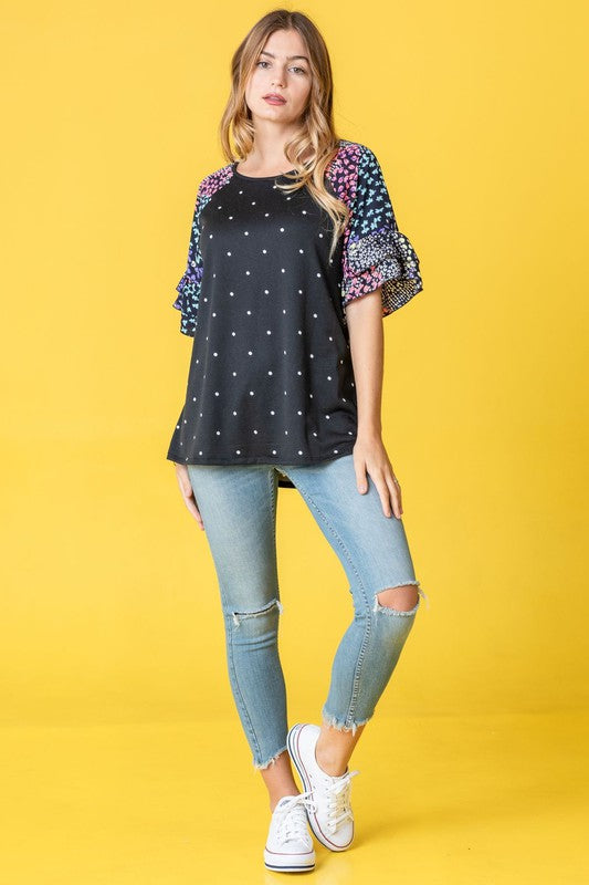 A person wearing the Polka Dot Print Ruffle Sleeve Top is standing against a bold yellow background.