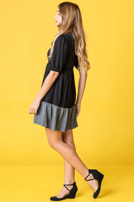 A person with long dark hair wearing a Plus Two Tone Tiered Mini Dress stands smiling in front of a light-colored curtain, showcasing her fashionable attire made in the United States.