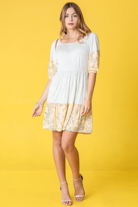 A woman wearing a Square Neck Floral Mini Dress poses elegantly against a vibrant yellow background.