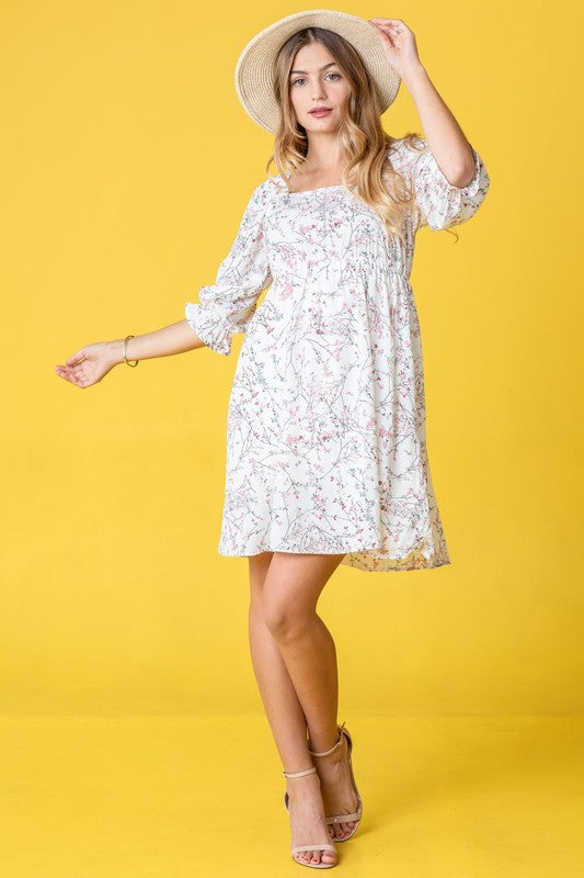 Dressed in the Branch Floral Squared Neck Mini Dress, a woman poses gracefully in front of a pink curtain.