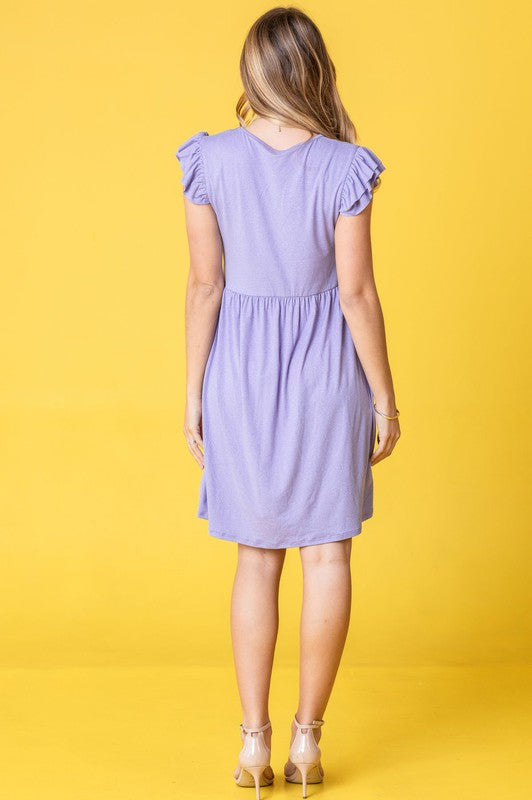 A woman wearing the Plus Solid Ruffle Cap Sleeve Midi Dress stands against a pink backdrop, looking down and gently holding her hair.