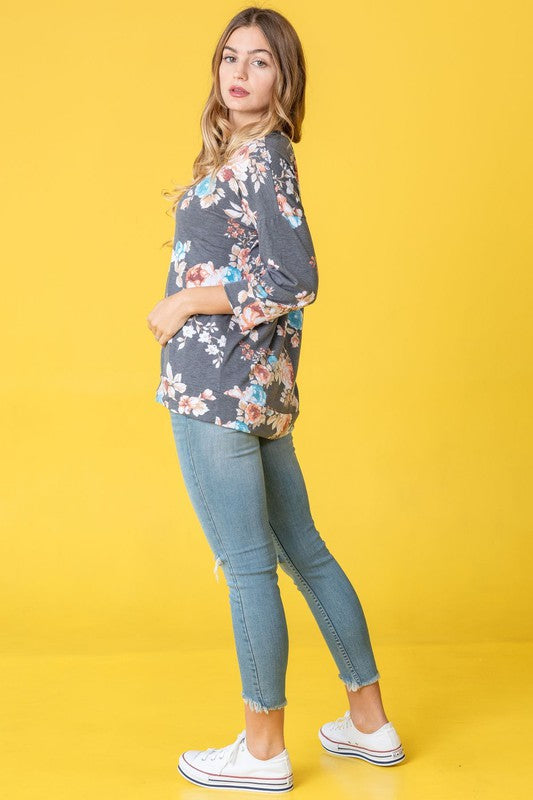 A woman wearing the Spring Floral Tunic and jeans stands against a vibrant yellow background, capturing the essence of spring.