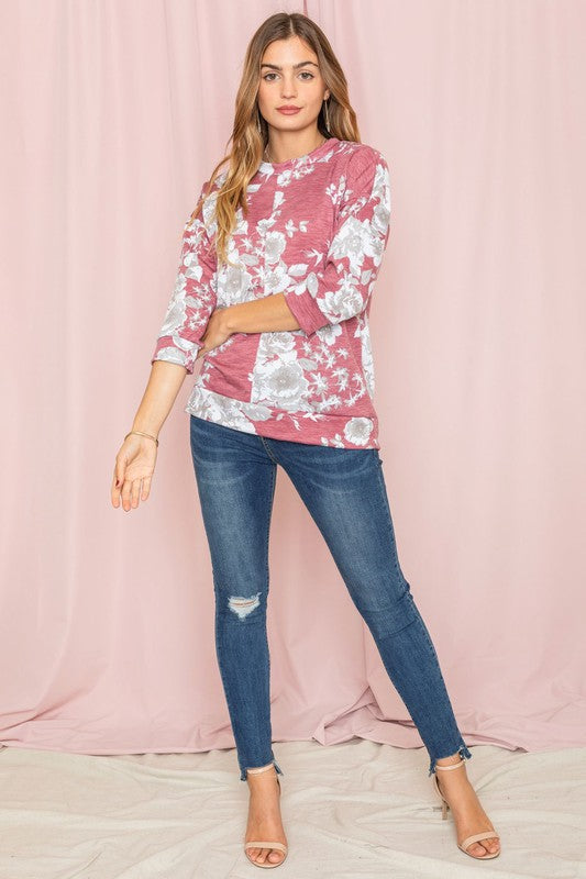 A woman wearing the Spring Floral Tunic and jeans stands against a vibrant yellow background, capturing the essence of spring.