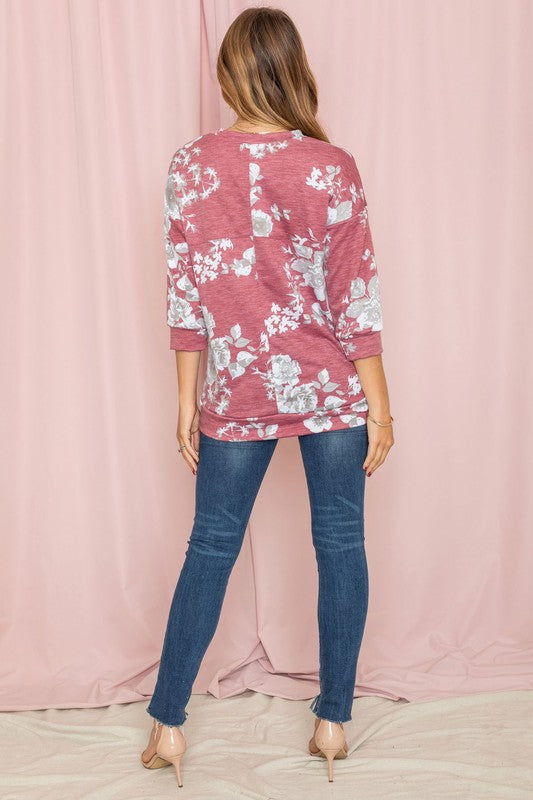 A woman wearing the Spring Floral Tunic and jeans stands against a vibrant yellow background, capturing the essence of spring.