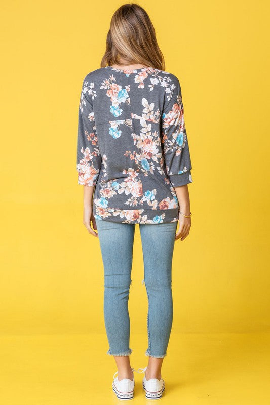 A woman wearing the Spring Floral Tunic and jeans stands against a vibrant yellow background, capturing the essence of spring.