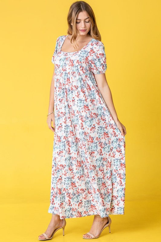 Woman in a Floral Square Neck Puff Sleeve dress stands against a pink backdrop.