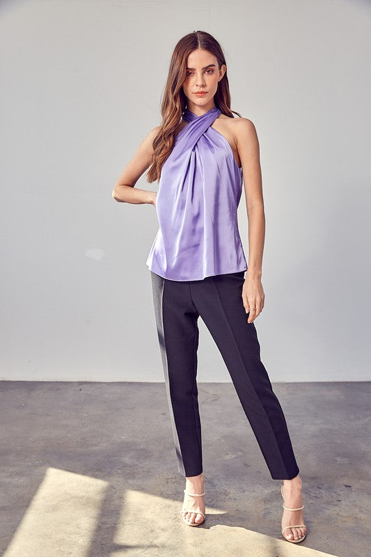 A woman wearing the stylish Cross Neck Top in lavender, paired with black pants, stands against a neutral background.