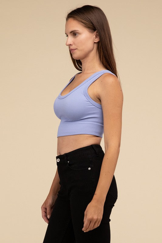 A person with long brown hair wearing the Ribbed Seamless Crop Top in light blue and black pants stands against a beige background, showcasing a perfect summer essential.