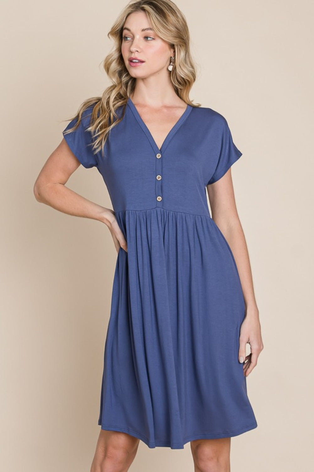 The BOMBOM V-Neck Short Sleeve Dress, crafted from soft rayon spandex fabric, showcases a blue hue with short sleeves and distinctive button accents.