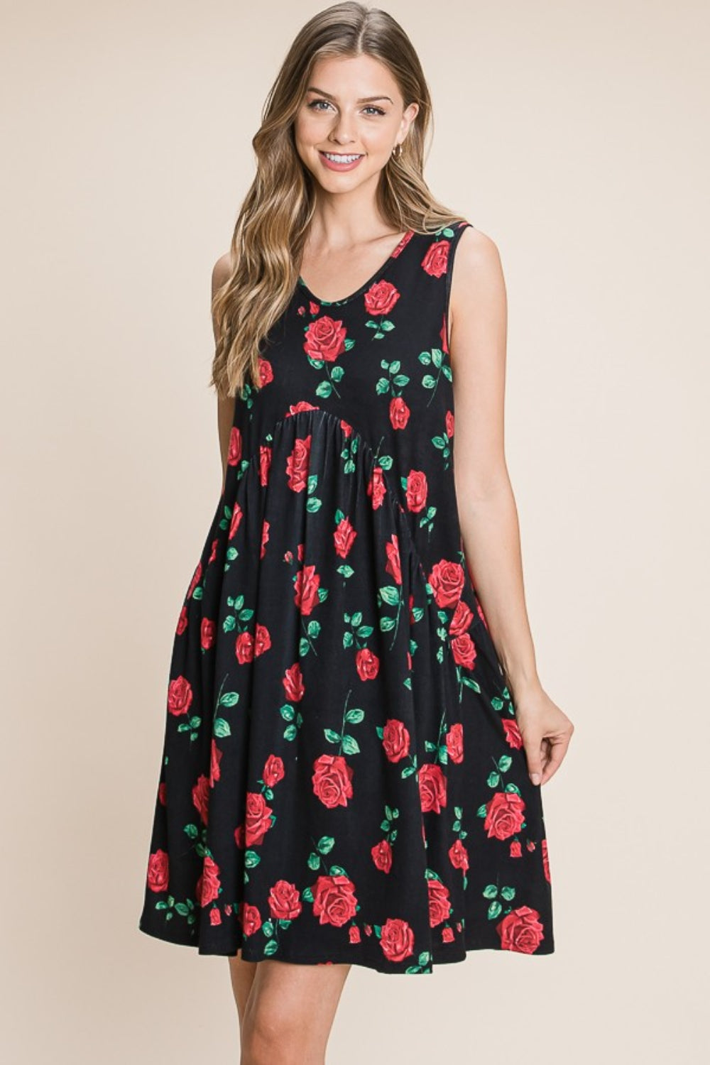 A woman is wearing a sleeveless BOMBOM Floral Ruched Tank Dress adorned with a black and red rose pattern. She is smiling and standing against a neutral background.