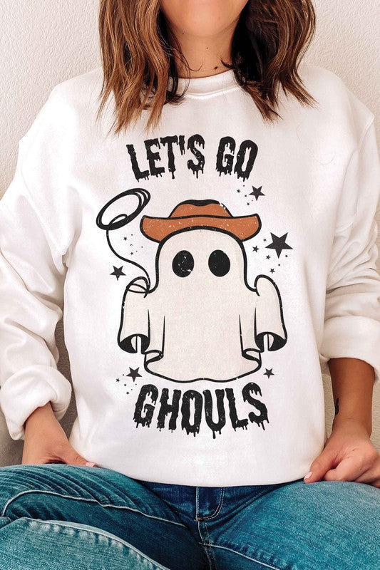 Individual adorned in a LETS GO GHOULS Graphic Crewneck, characterized by a beige hue and featuring a ghost donning a cowboy hat along with the text "Let's Go Ghouls.