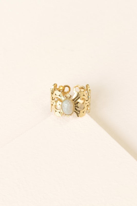 Presenting the Perdita Adjustable Ring—a bohemian treasure. This 14k gold-plated piece boasts an intricate design, highlighting a central oval gemstone beautifully set against a light background.