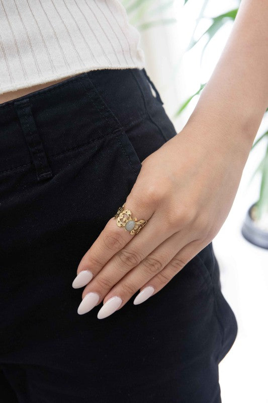 Presenting the Perdita Adjustable Ring—a bohemian treasure. This 14k gold-plated piece boasts an intricate design, highlighting a central oval gemstone beautifully set against a light background.