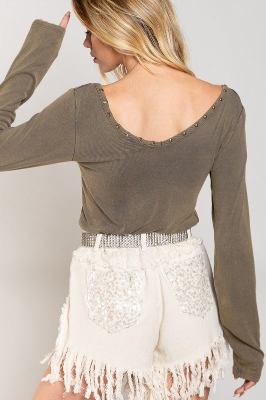 A woman wearing the Studded Ribbed V-Neck Top paired with white distressed shorts and a jeweled belt.