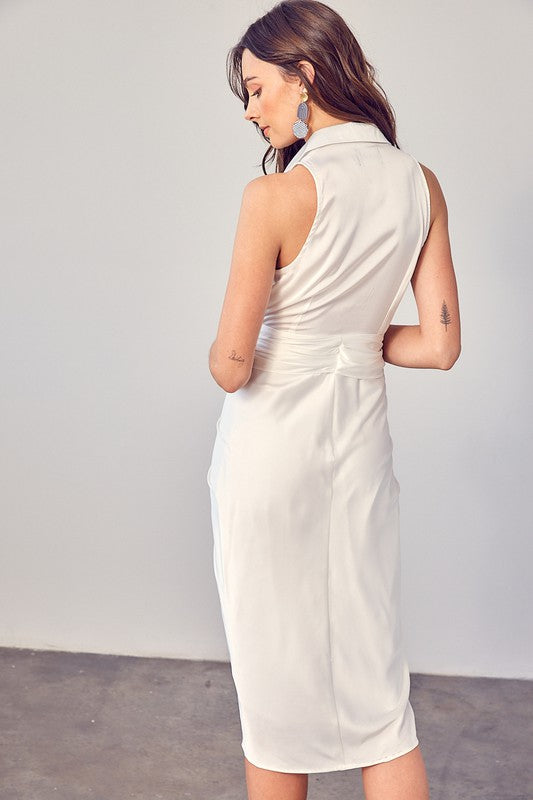 A woman stands indoors against a plain background, elegantly wearing the Sleeveless Collared Front Tie Dress in white.