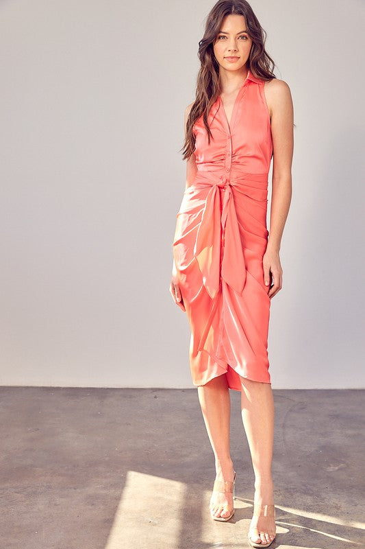 A woman wearing the Sleeveless Collar Front Tie Dress in coral, standing against a plain backdrop.