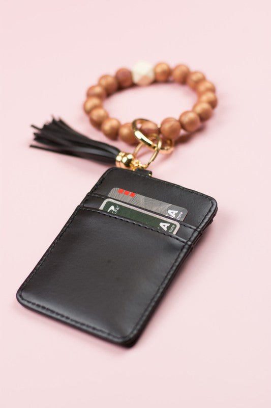 A person wearing a Silicone Key Ring Wallet Bracelet holds a small black wallet on a key ring, showcasing a hands-free design.