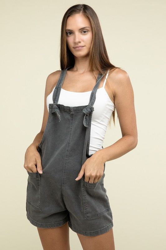 A person wearing the Washed Knot Strap Romper and a white tank top stands against a plain background.