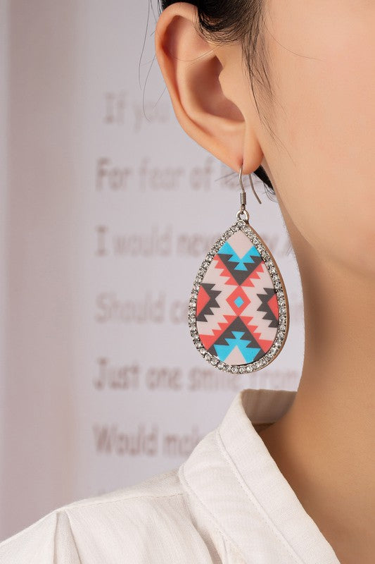 Introducing the Teardrop Aztec drop earrings with rhinestones, featuring a vibrant geometric pattern inspired by Aztec designs and highlighted with shimmering glass rhinestones set against a beige backdrop.